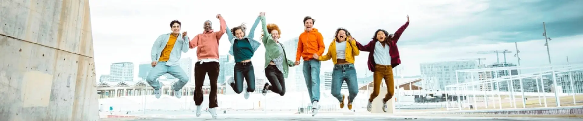 Group of young people holding hands and jumping in the air together
