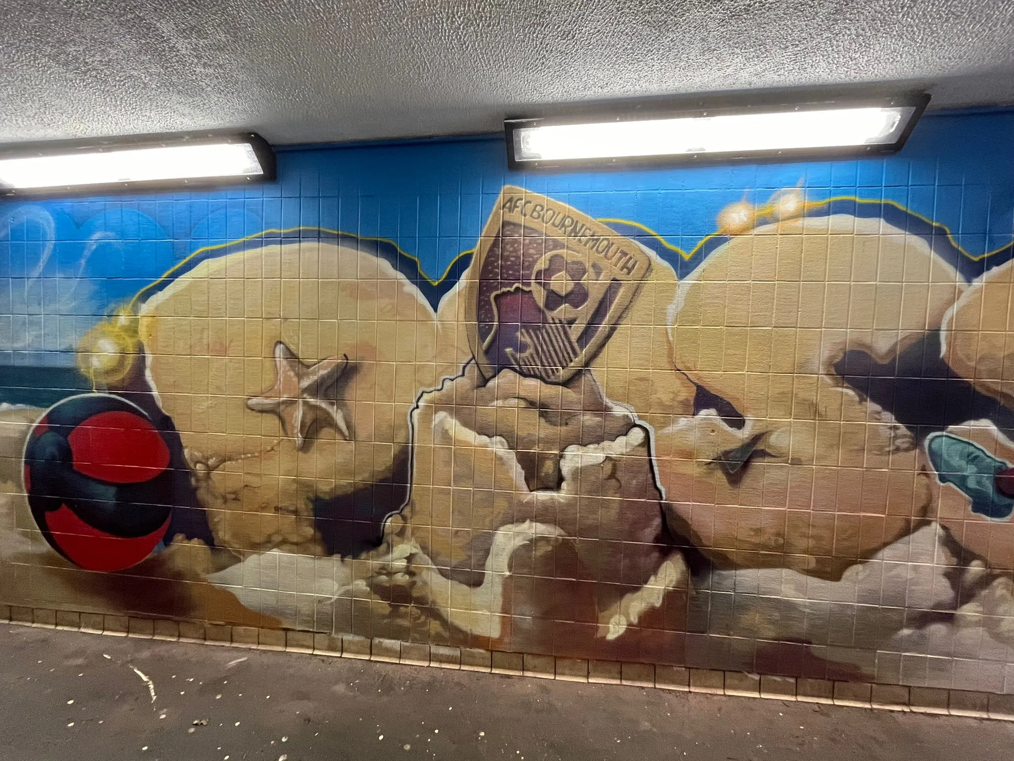 Underpass mural of a beach scene with sandcastles, a starfish, a beach ball and the AFC Bournemouth crest