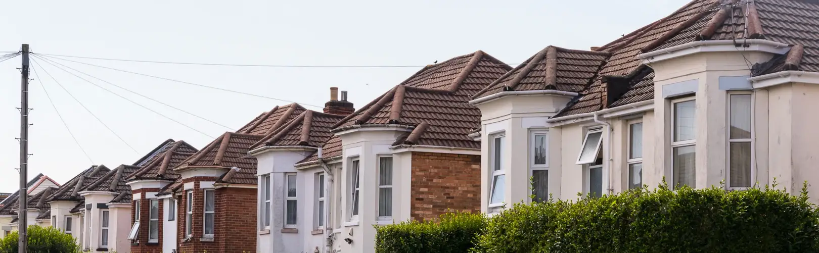 Row of red-roofed houses with bay windows along a Charminster street