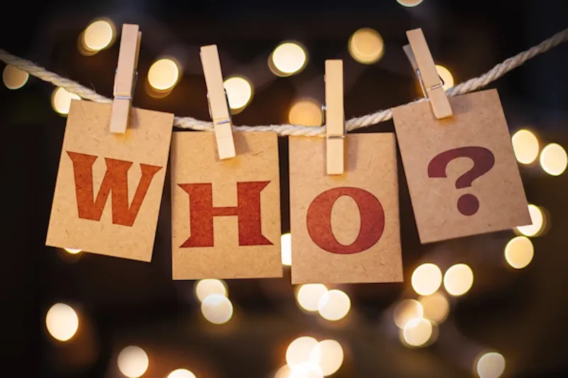 Cards spelling 'Who?' pegged to a string against twinkling lights